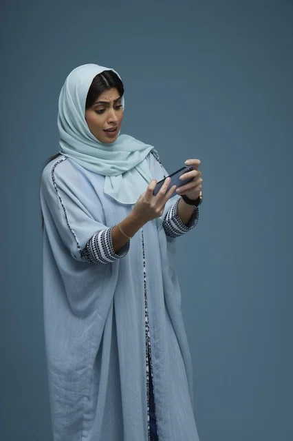 Saudi Woman Using Smartphone Against Blue Background