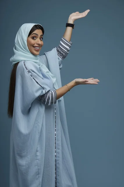 Saudi Woman Presenting with Open Hands on Blue Background