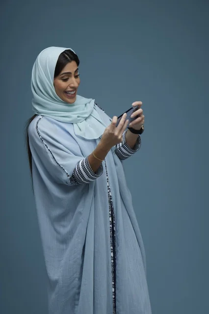 امرأة سعودية تستخدم الهاتف الذكي بخلفية زرقاء