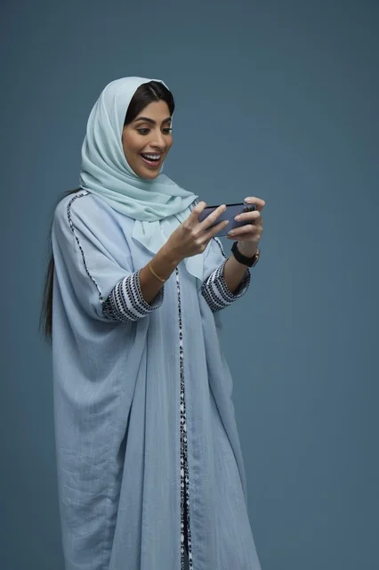 Saudi Woman Using Smartphone on Blue Background