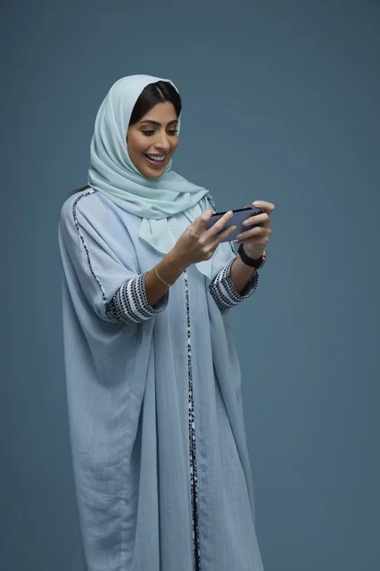 Saudi Woman Using Smartphone in Blue Abaya Studio Shot