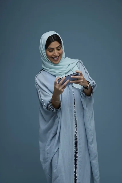 امرأة سعودية تستخدم الهاتف الذكي بالعباءة الزرقاء