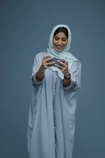 Saudi Woman with Smartphone on Blue Background