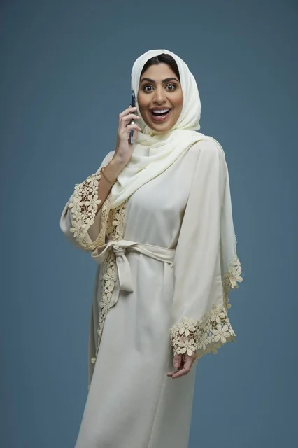 Saudi Woman in White Abaya Talking on Smartphone Saudi Woman in White Abaya Talking on Smartphone