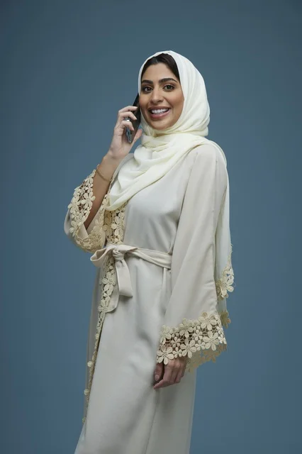 امرأة سعودية بعباءة بيضاء مطرزة تتحدث عبر الهاتف