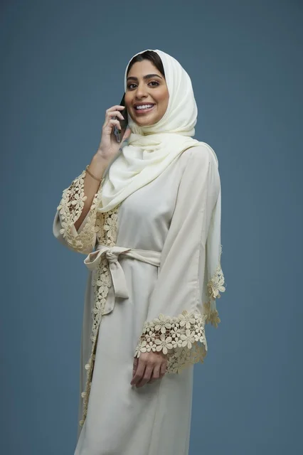 امرأة سعودية بعباءة بيضاء تتحدث عبر الهاتف الذكي