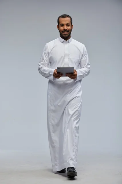 Saudi Man in White Thobe Holding Digital Tablet