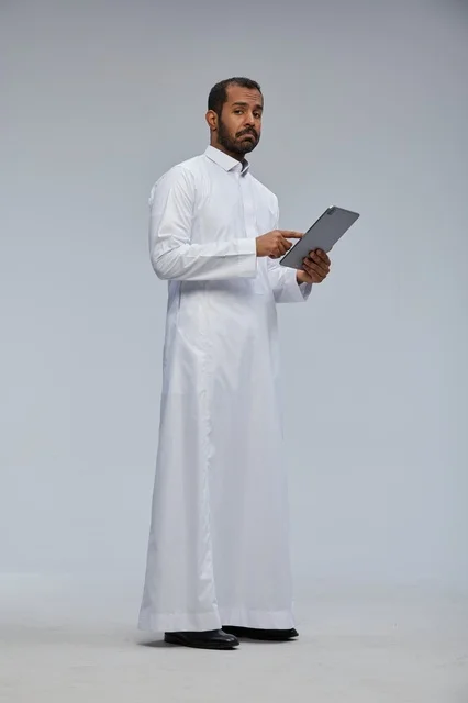 Saudi Man in White Thobe Using Digital Tablet in Studio
