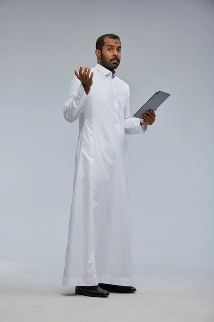 Saudi Man in White Thobe Using Digital Tablet