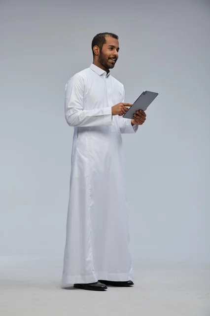 Saudi Man in White Thobe Using Digital Tablet in Studio