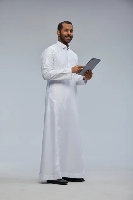 Saudi Man in White Thobe Using Digital Tablet