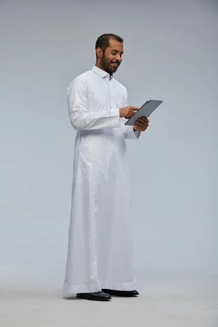 Saudi Man in White Thobe Using Tablet in Studio