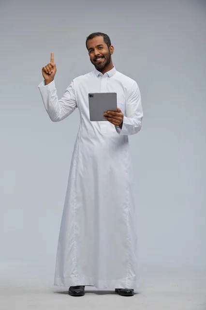 رجل سعودي بالثوب الأبيض يستخدم جهازاً لوحياً