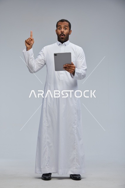 رجل سعودي يستخدم جهاز لوحي بتعبير مندهش