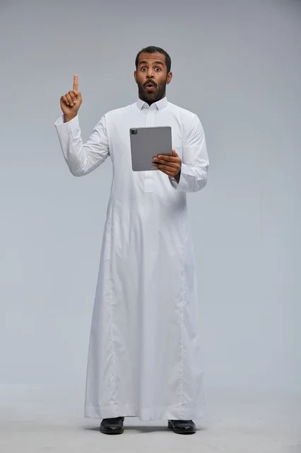 رجل سعودي يستخدم جهاز لوحي بتعبير مندهش