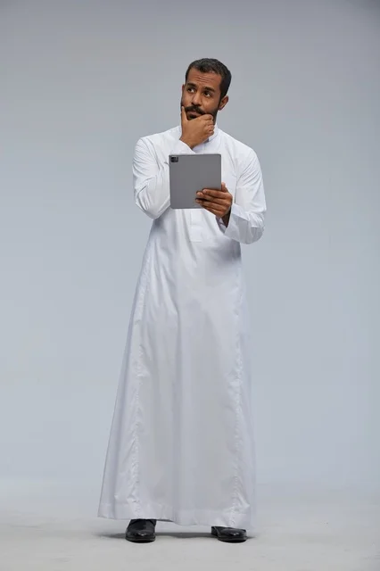 Saudi Man in White Thobe Using Tablet