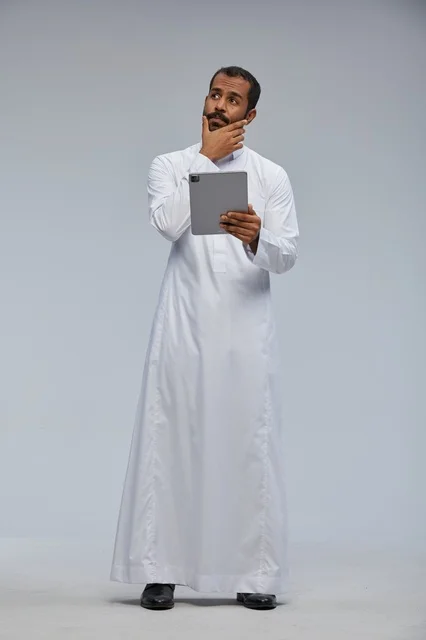 Saudi Man in White Thobe Holding a Tablet Thinking