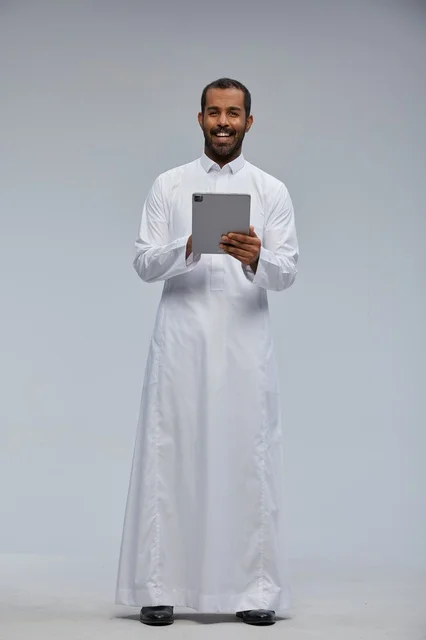 Saudi Man in White Thobe Using Digital Tablet