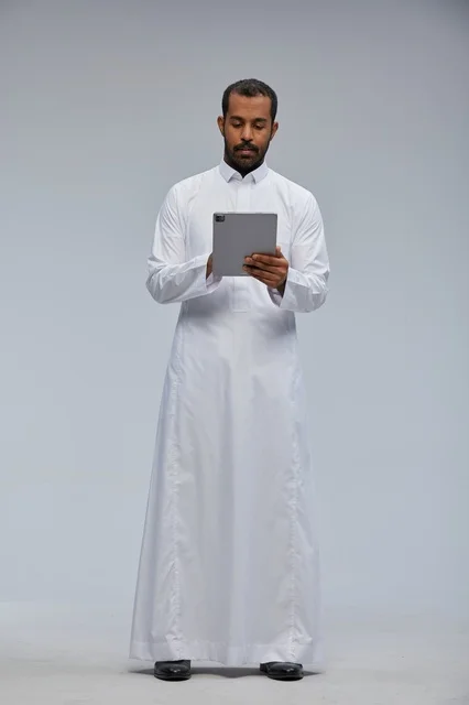 Saudi Man in White Thobe Using Digital Tablet