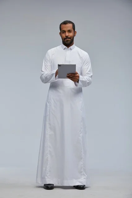 Saudi Man in Thobe Using Tablet on Grey Background