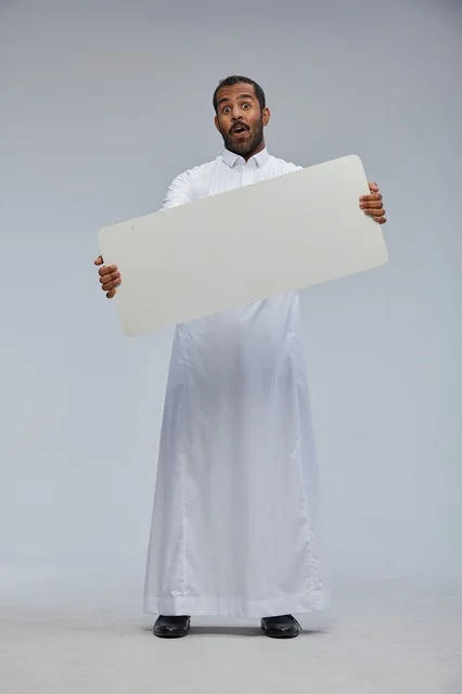 رجل سعودي بالزي التقليدي يحمل لوحة بيضاء فارغة