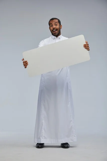رجل سعودي بالزي التقليدي يحمل لوحة بيضاء فارغة