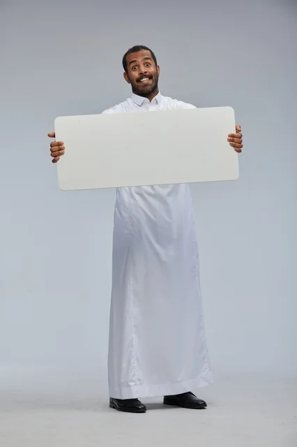 Smiling Saudi man holding a blank signboard in traditional attire
