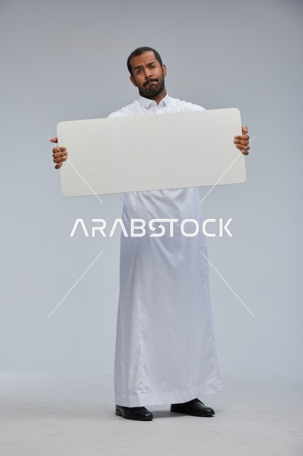 رجل سعودي بالثوب التقليدي يحمل لوحة بيضاء فارغة