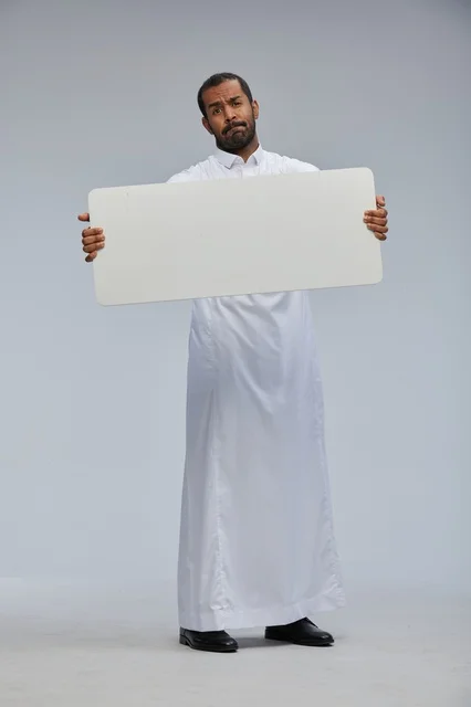 رجل سعودي بالثوب التقليدي يحمل لوحة بيضاء فارغة