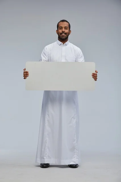 رجل سعودي بالزي التقليدي يحمل لوحة بيضاء فارغة