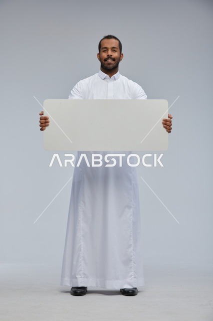 رجل سعودي يحمل لوحة بيضاء فارغة في الاستوديو