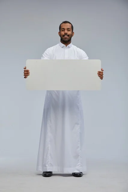 رجل سعودي يحمل لوحة بيضاء فارغة في الاستوديو
