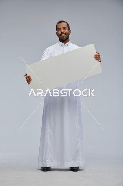 رجل سعودي بالثوب التقليدي يحمل لوحة بيضاء فارغة