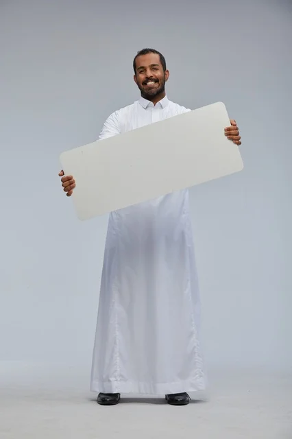 رجل سعودي بالثوب يحمل لوحة بيضاء فارغة