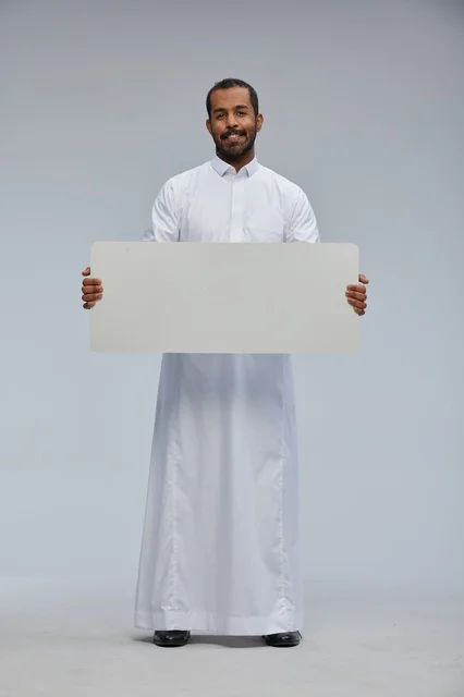 رجل سعودي بالزي التقليدي يحمل لوحة بيضاء فارغة للإعلانات