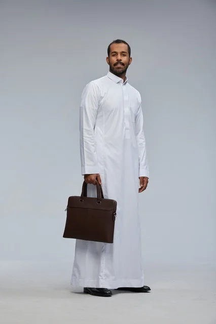 رجل أعمال سعودي بالثوب التقليدي يحمل حقيبة عمل جلدية