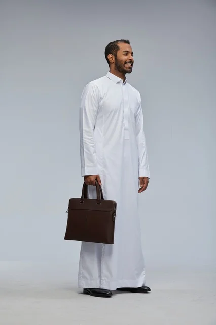 رجل أعمال سعودي يحمل حقيبة عمل بالثوب الأبيض الرسمي