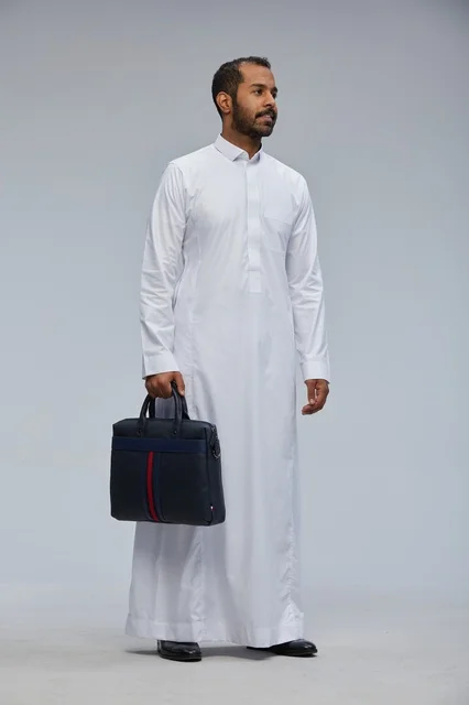 رجل أعمال سعودي بالثوب يحمل حقيبة عمل في الاستوديو