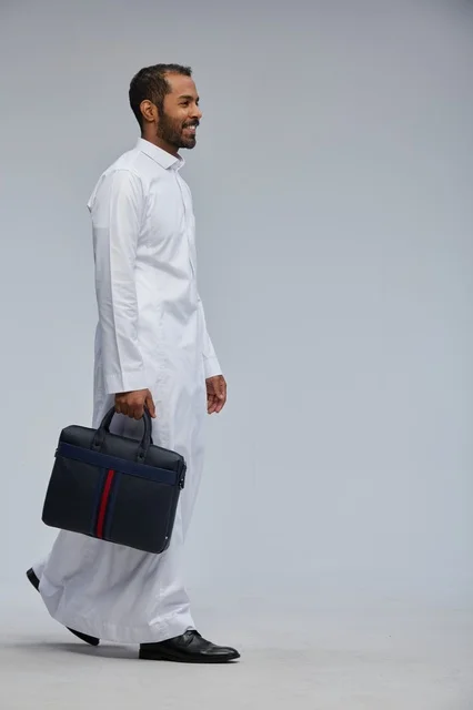 رجل أعمال سعودي يحمل حقيبة عمل بالزي التقليدي الرسمي
