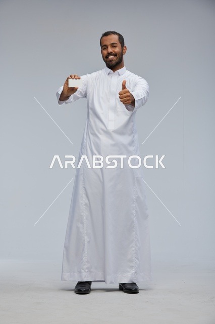 رجل سعودي بالثوب يمسك بطاقة فارغة وعلامة إعجاب