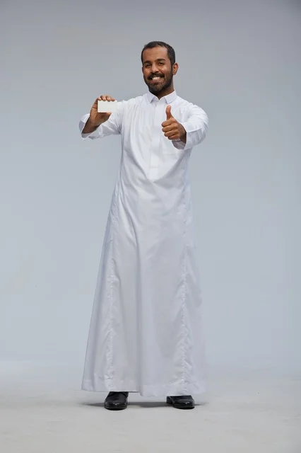 Smiling Saudi Man in Traditional Thobe Holding Blank Card Smiling Saudi Man in Traditional Thobe Holding Blank Card