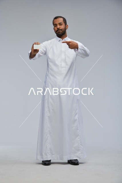 رجل سعودي بالثوب التقليدي يمسك بطاقة عمل فارغة