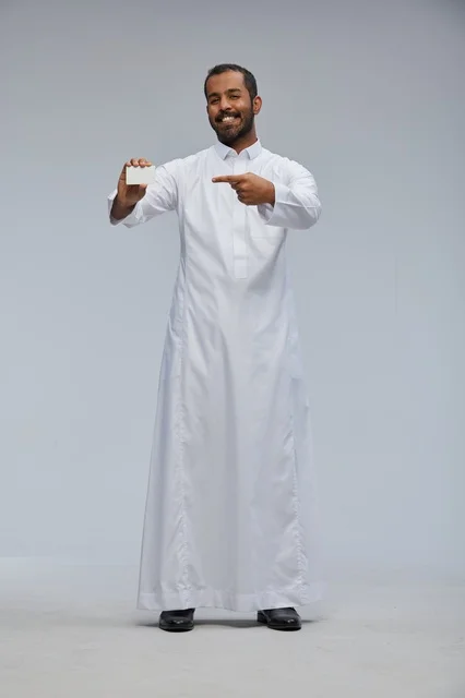 رجل سعودي يرتدي الثوب التقليدي يمسك بطاقة بيضاء فارغة