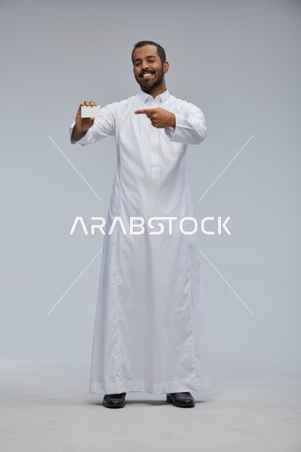رجل سعودي مبتسم يمسك بطاقة عمل فارغة