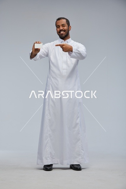 رجل سعودي مبتسم يحمل بطاقة عمل بيضاء فارغة