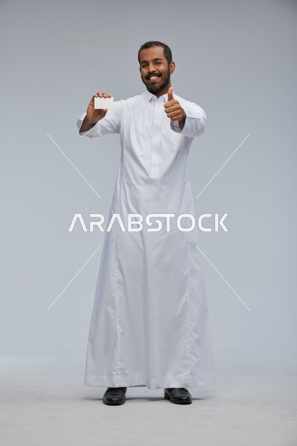 رجل سعودي بالثوب يحمل بطاقة فارغة مع إشارة الإبهام