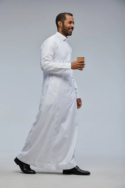 Saudi Man in Traditional Thobe Walking with Coffee Cup