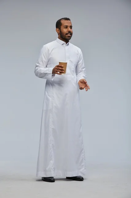 رجل سعودي بالزي التقليدي يحمل كوب قهوة