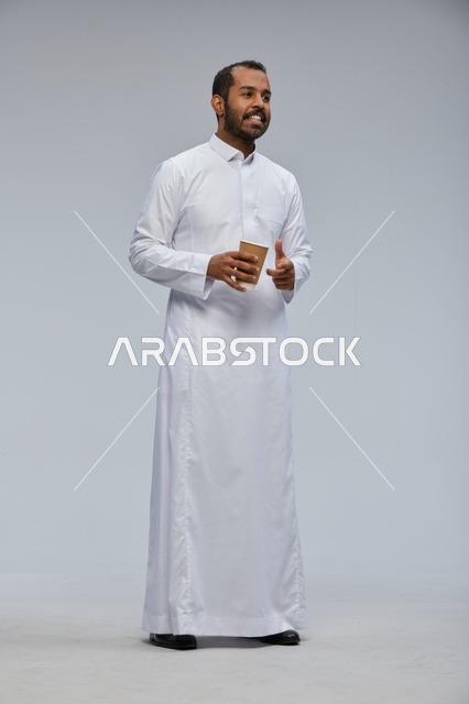 رجل سعودي بالثوب يحمل كوب قهوة مبتسم