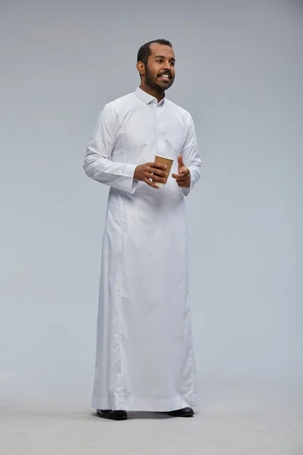 رجل سعودي بالثوب يحمل كوب قهوة مبتسم